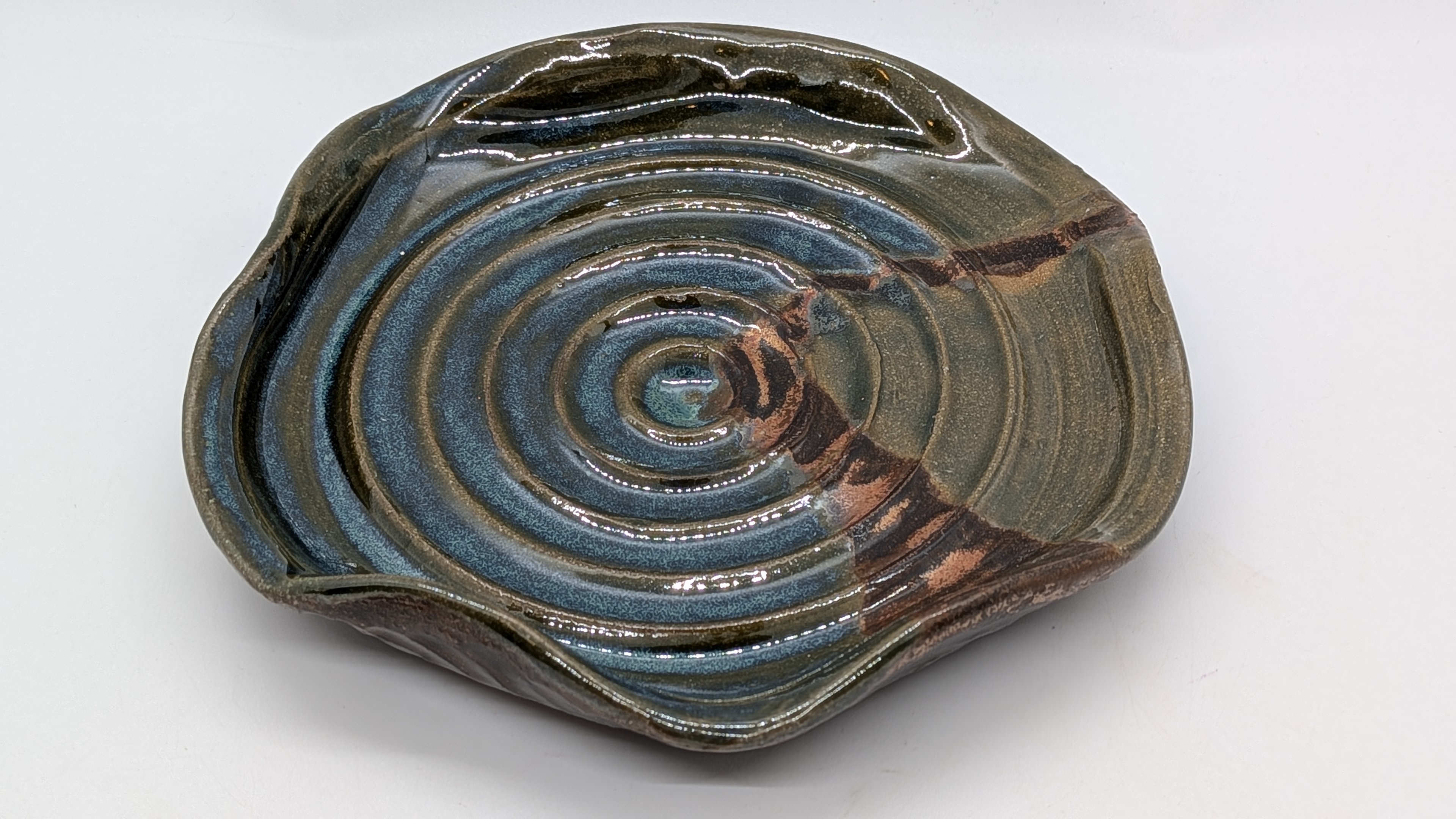 Funky Spoon Rest - This is an extra-large spoon rest that you could also use for snacks! It's got a great, foresty-green color with hints of bark-colored copper and river-like shimmers of blues and grays. With scalloped edges, it's a fun, unique piece for daily use in your kitchen! 

It's a nice complement to just about any of my prep bowl sets, thanks to its relatively neutral coloring.  - 18